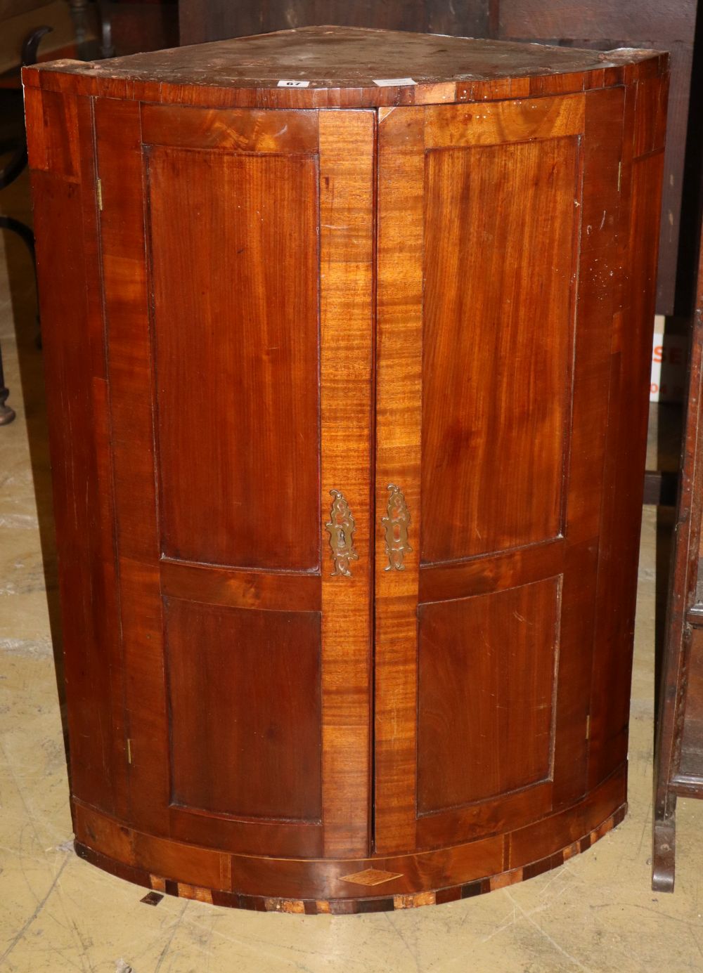 A Regency banded mahogany bow fronted hanging corner cupboard (a.f.), W.70cm, D.44cm, H.100cm